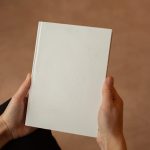 A person holding a blank hardcover book. Perfect for mockup and design templates.